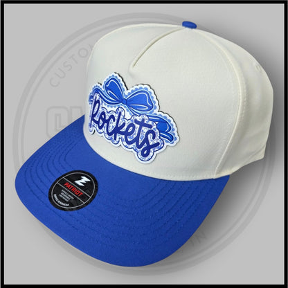 Cream and blue baseball cap, angled view with blue script logo patch and Patriot badge