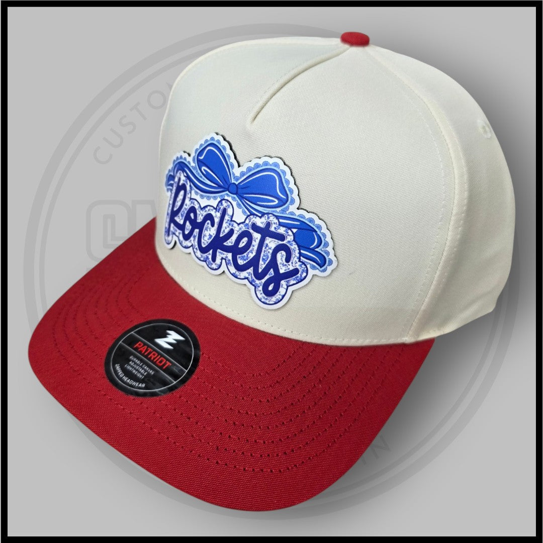 Cream crown and red brim baseball cap, angled view with blue script logo patch