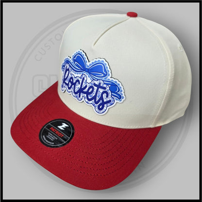 Cream crown and red brim baseball cap, angled view with blue script logo patch