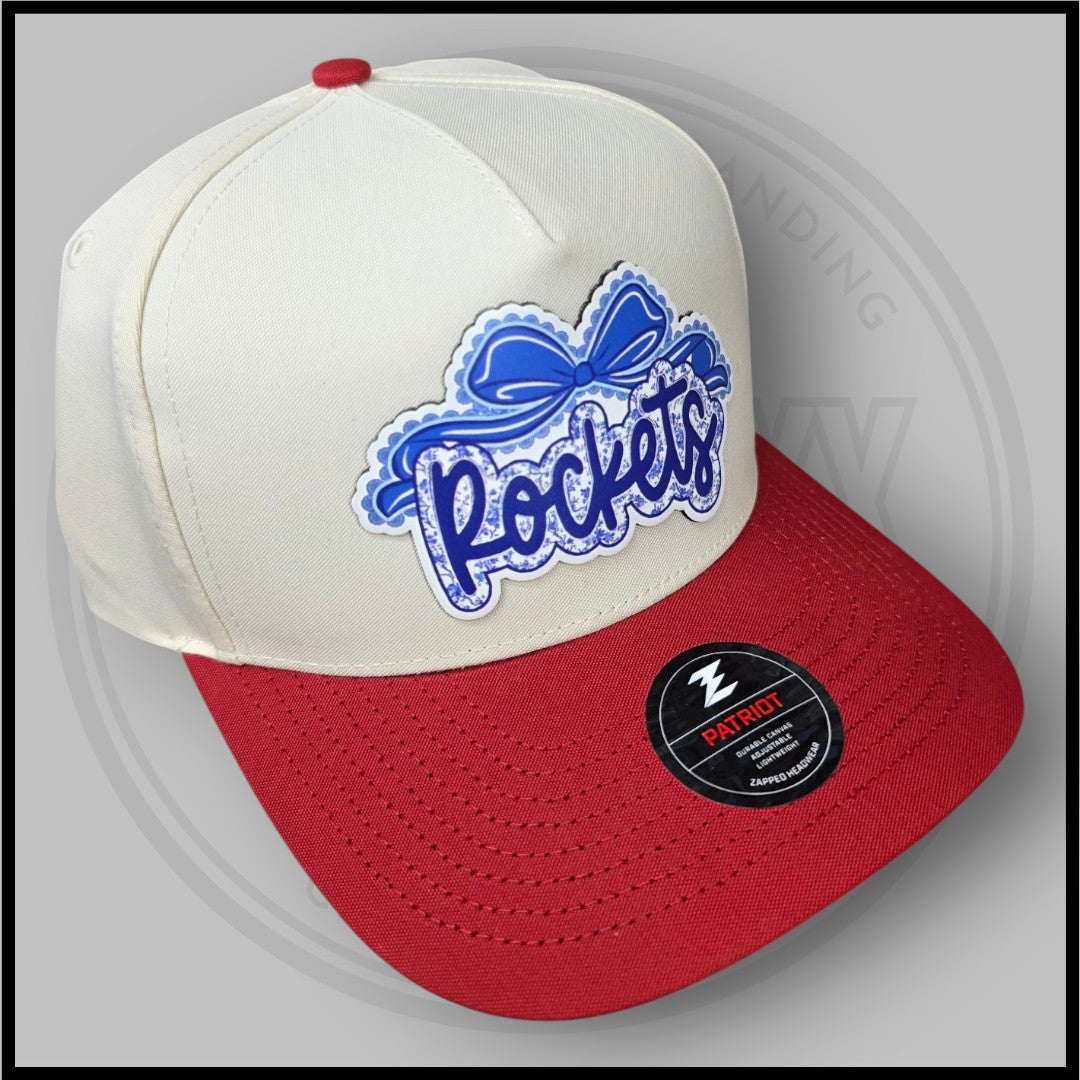 Cream and red baseball cap with blue script logo patch and Patriot badge on side