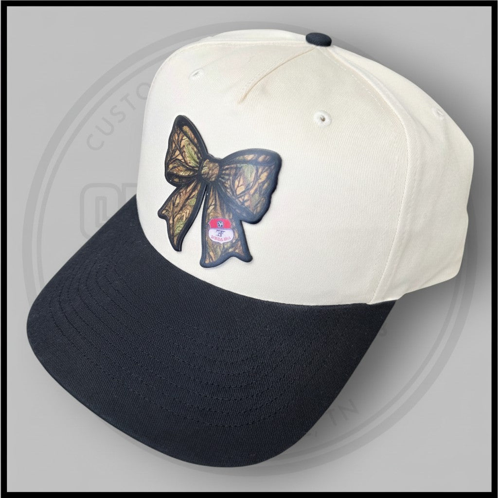 Two-tone baseball cap with cream crown, black brim, and large bow applique on side