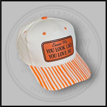 Tilted view white baseball cap with orange striped lower panel and slogan patch