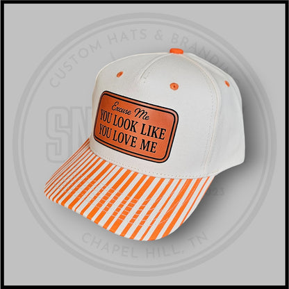 White baseball cap with orange striped brim and front slogan logo patch