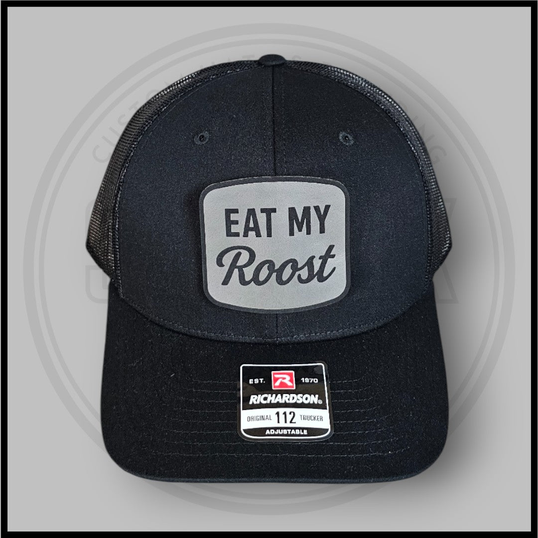 Dark charcoal trucker baseball cap with front Eat My Roost oval patch and Richardson label