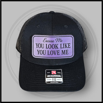 Black trucker cap with purple-bordered 'Excuse Me You Look Like You Love Me' front patch