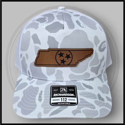 White duck camo trucker cap with brown logo patch and adjustable strap, mesh back